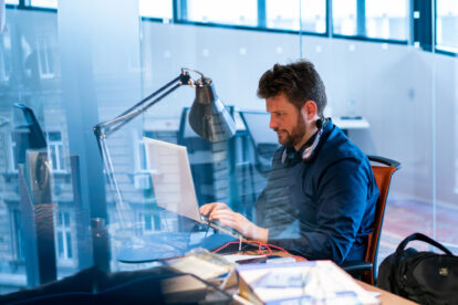 focused-male-computer-programmer-working-on-laptop-at-desk-in-office