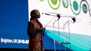 Woman on stage presenting her Lightning Talk at TNC25