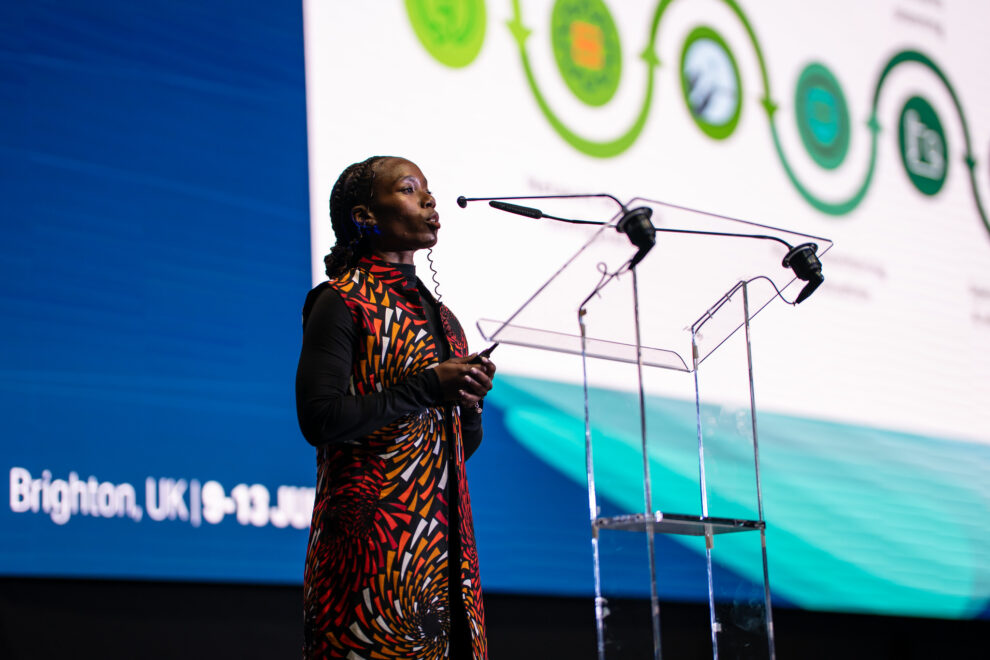 Woman on stage presenting her Lightning Talk at TNC25